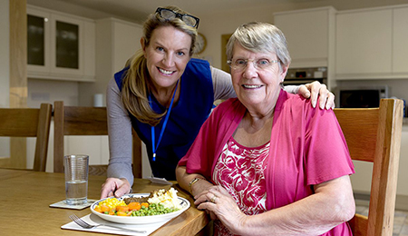 A volunteer delivering a meal to an older adult