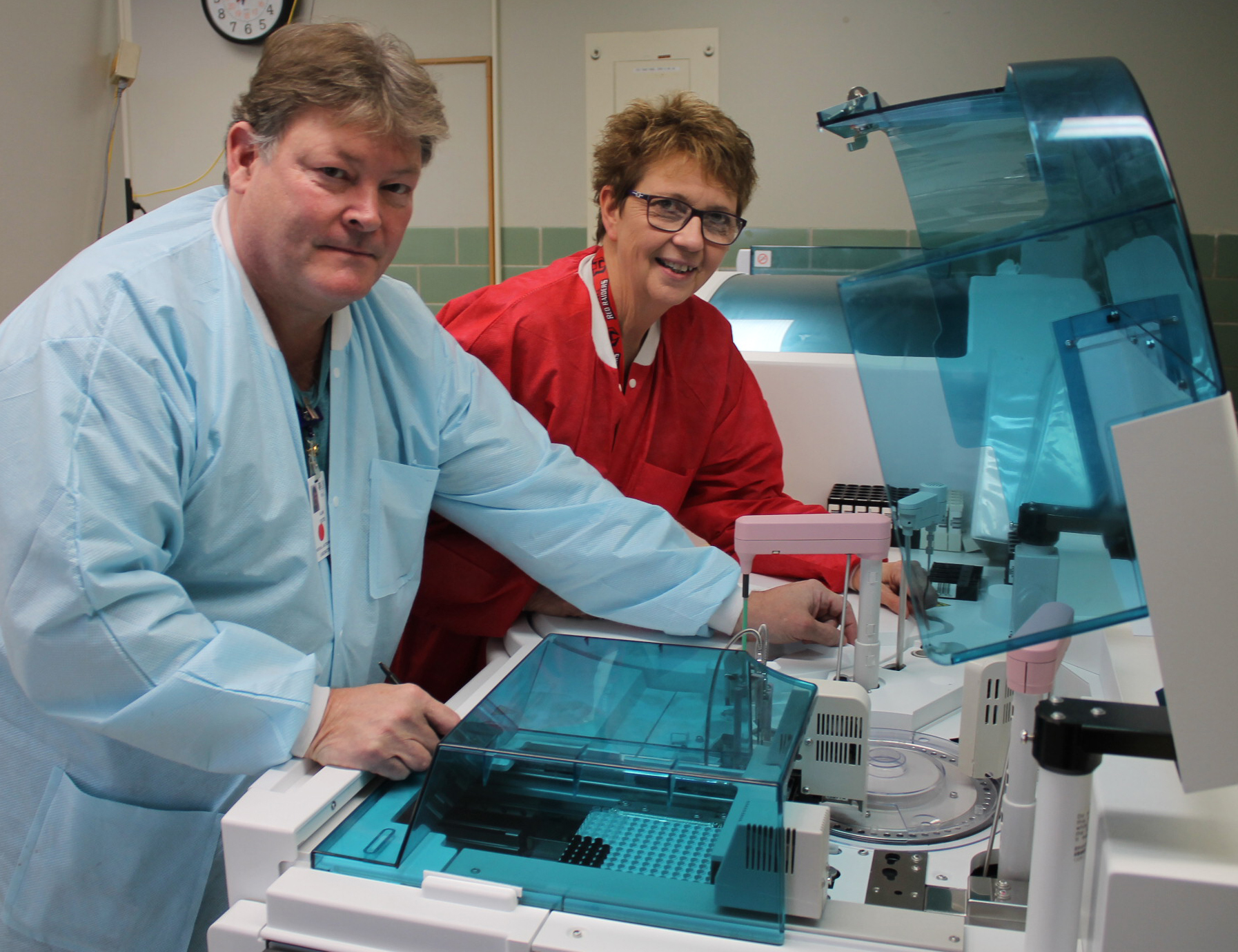An man and woman working together on a complex machine in a laboratory setting.