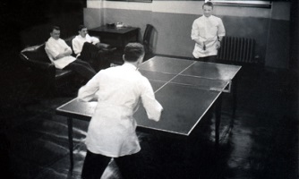 Drs. Altinsall and Elwood play ping pong while other residents watch.