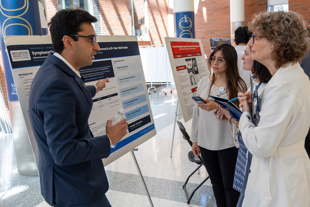 Muhammad Hamza Asif, MD (left) discusses his poster with judges