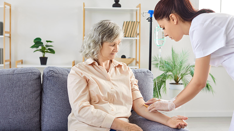 older woman receiving infusion treatment in her arm from nurse