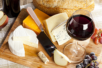 photo of a wedge of cheddar cheese and a glass of red wine