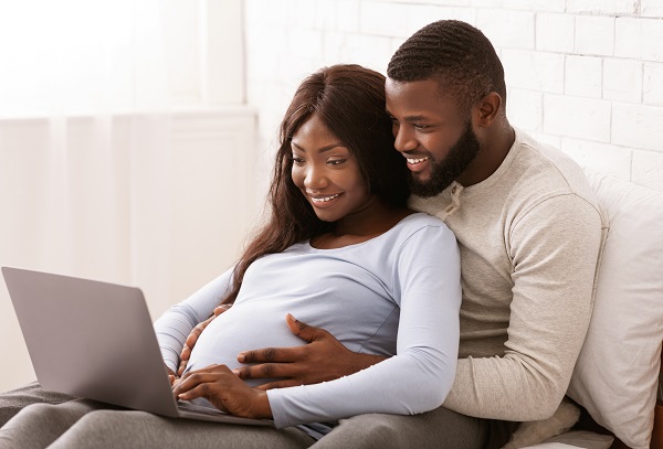 Pregnant couple looking at laptop