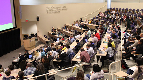 people sitting in an auditorium watching presentation