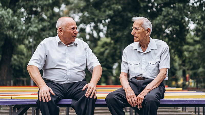 two older men talking on park bench