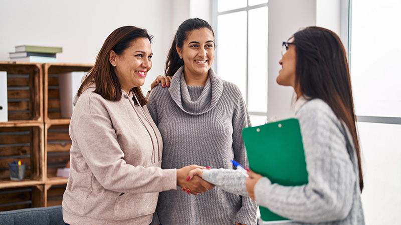 counselor shaking hand of mother and daughter