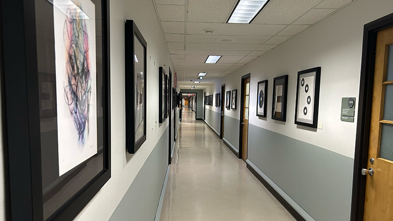 artwork displayed hanging on walls down an hallway