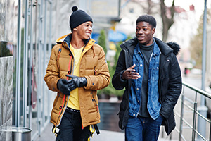 two young men walking down the street talking