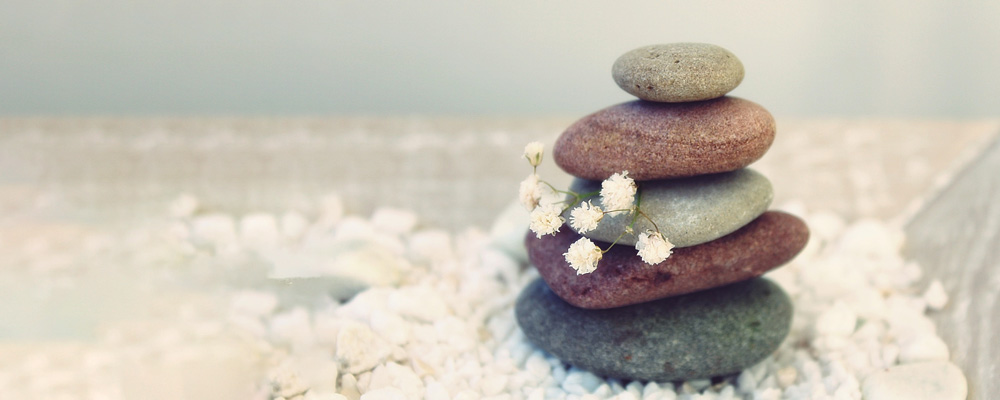 smooth rocks stacked on top of one another with a white flower