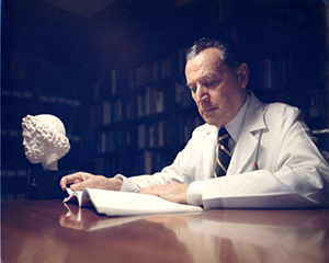 Dr. John Romano reading a book at a desk