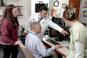 A group of people sitting around viewing a computer screen.