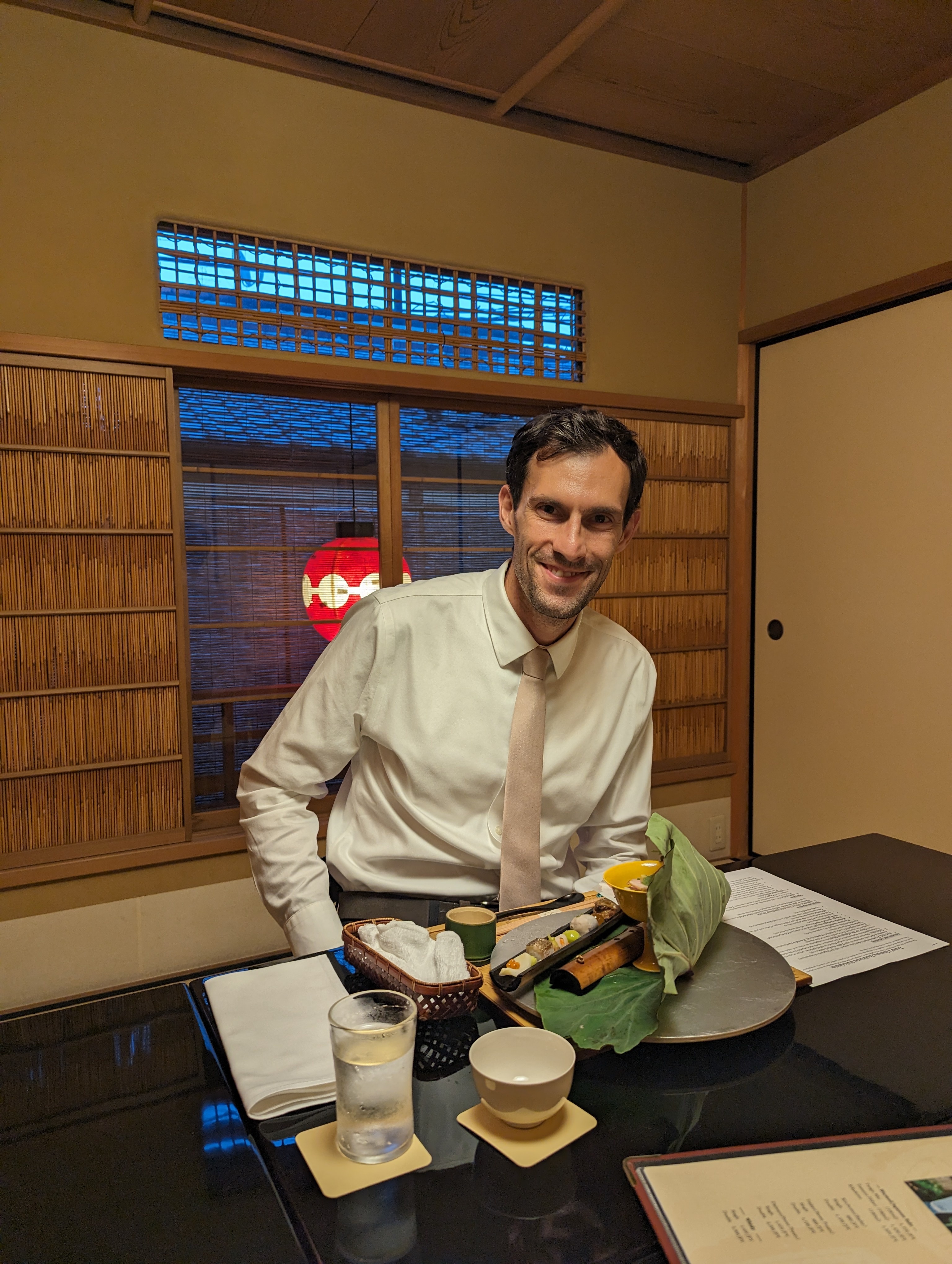Phil Spinelli smiling and sitting at a table in Japan eating a dinner
