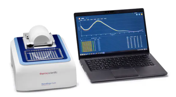 The nanodrop eight instrument is on the left and an open laptop with a nanodrop spectral plot appears on the screen.