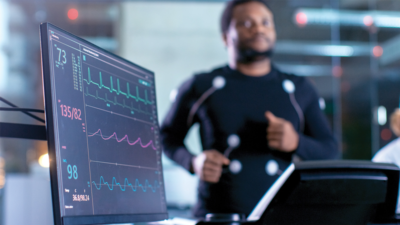 Man running on treatmill with heart rate monitors on.