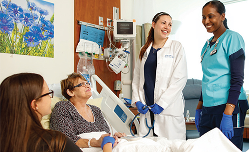 Patient in bed smiling at members of care team in the hospital