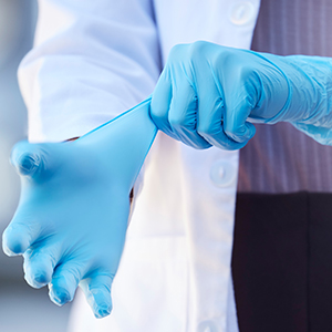 Nurse putting on blue rubber gloves