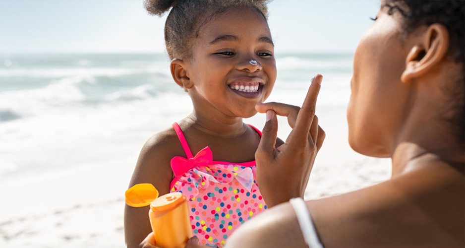 Woman applying sunscreen to a child on the beach