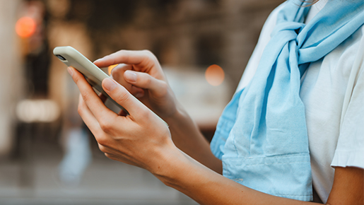 Image of a person wearing a blue sweater holding a cellphone