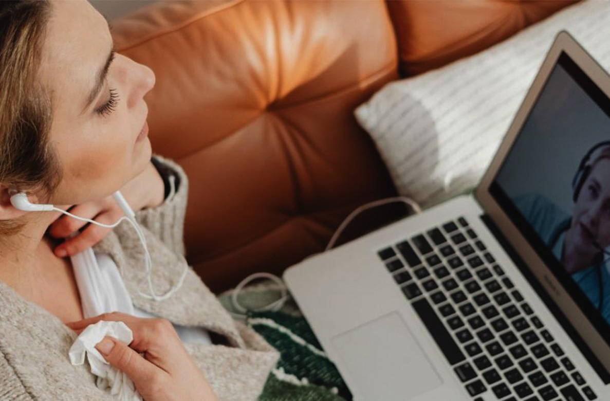 Woman on a couch with tissues with a laptop on a telemedicine appointment