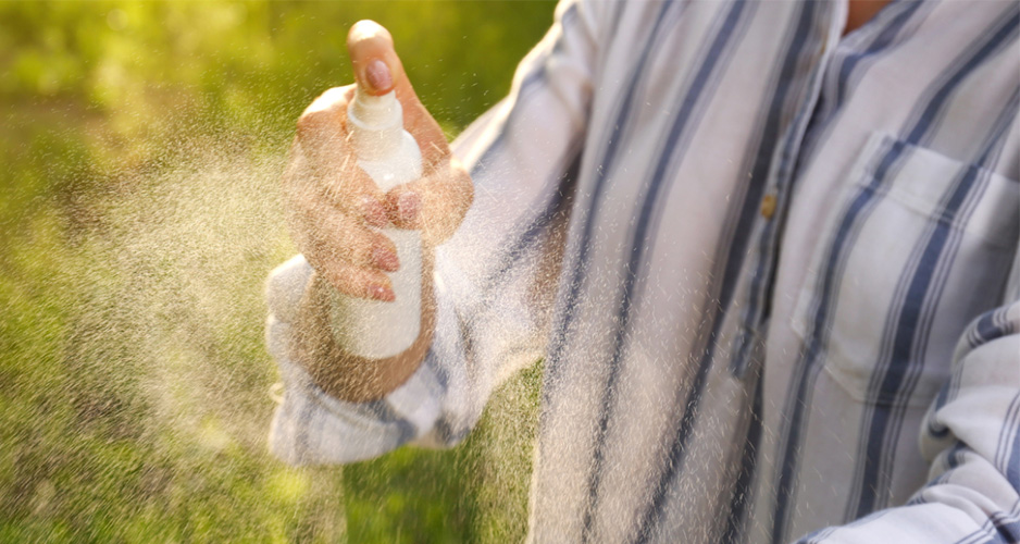 Person spraying bug spray outside