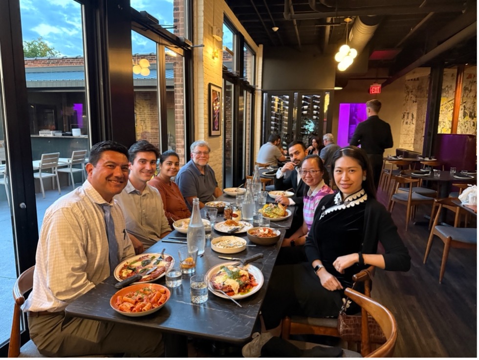 A diverse group of individuals sitting at a table, happily eating and chatting.
