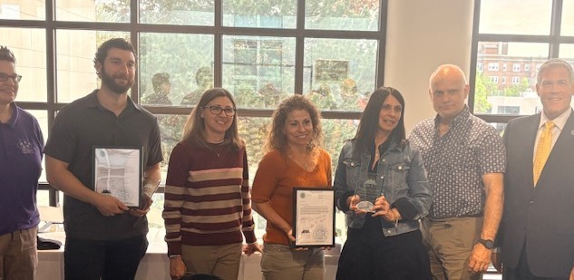 Group of Monroe Country Got Dreams Awardees holding certificates and smiling at the camera. They are standing by Monroe County Monroe County Executive Adam J. Bello